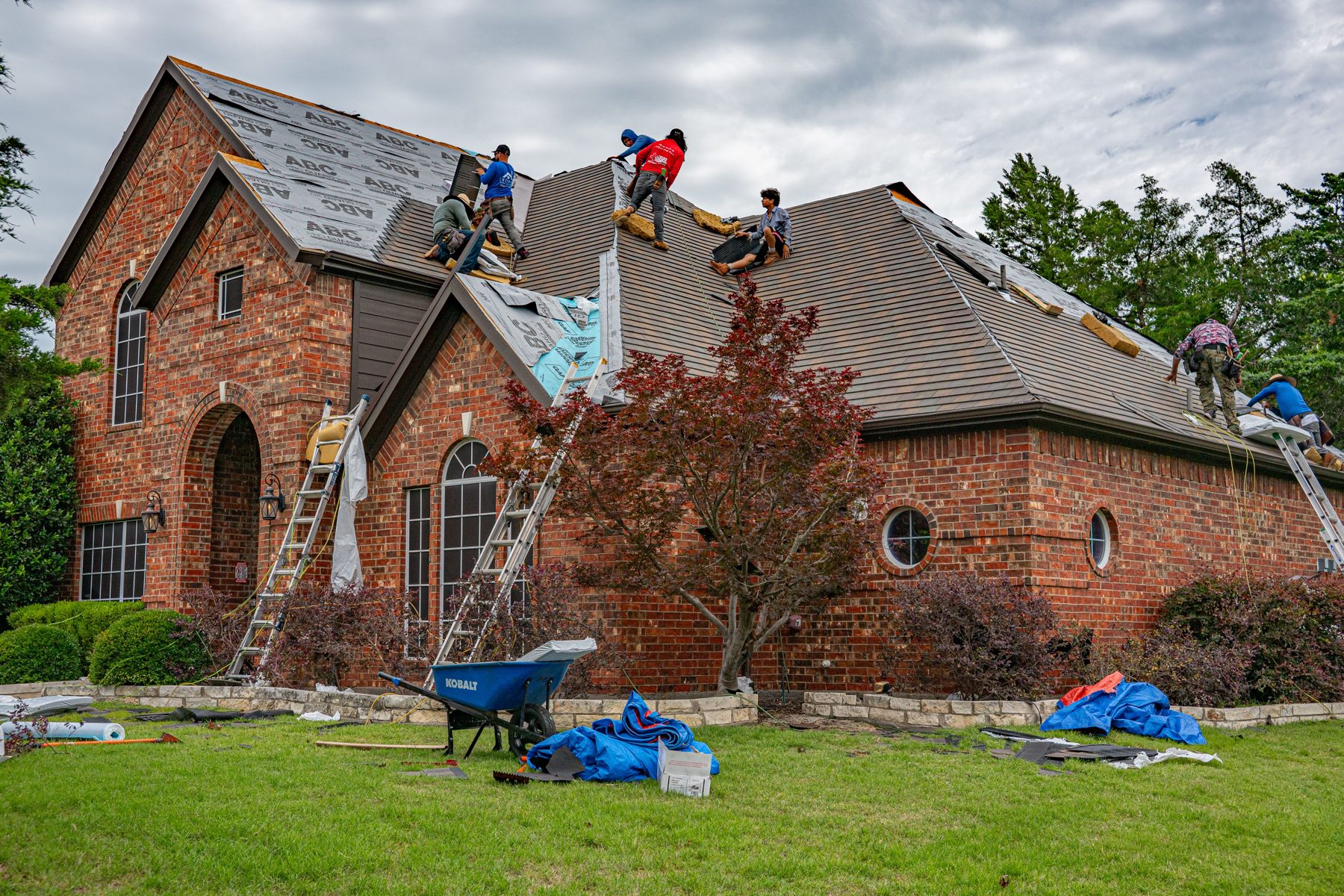 Roofing crew replacing shingles on a brick home